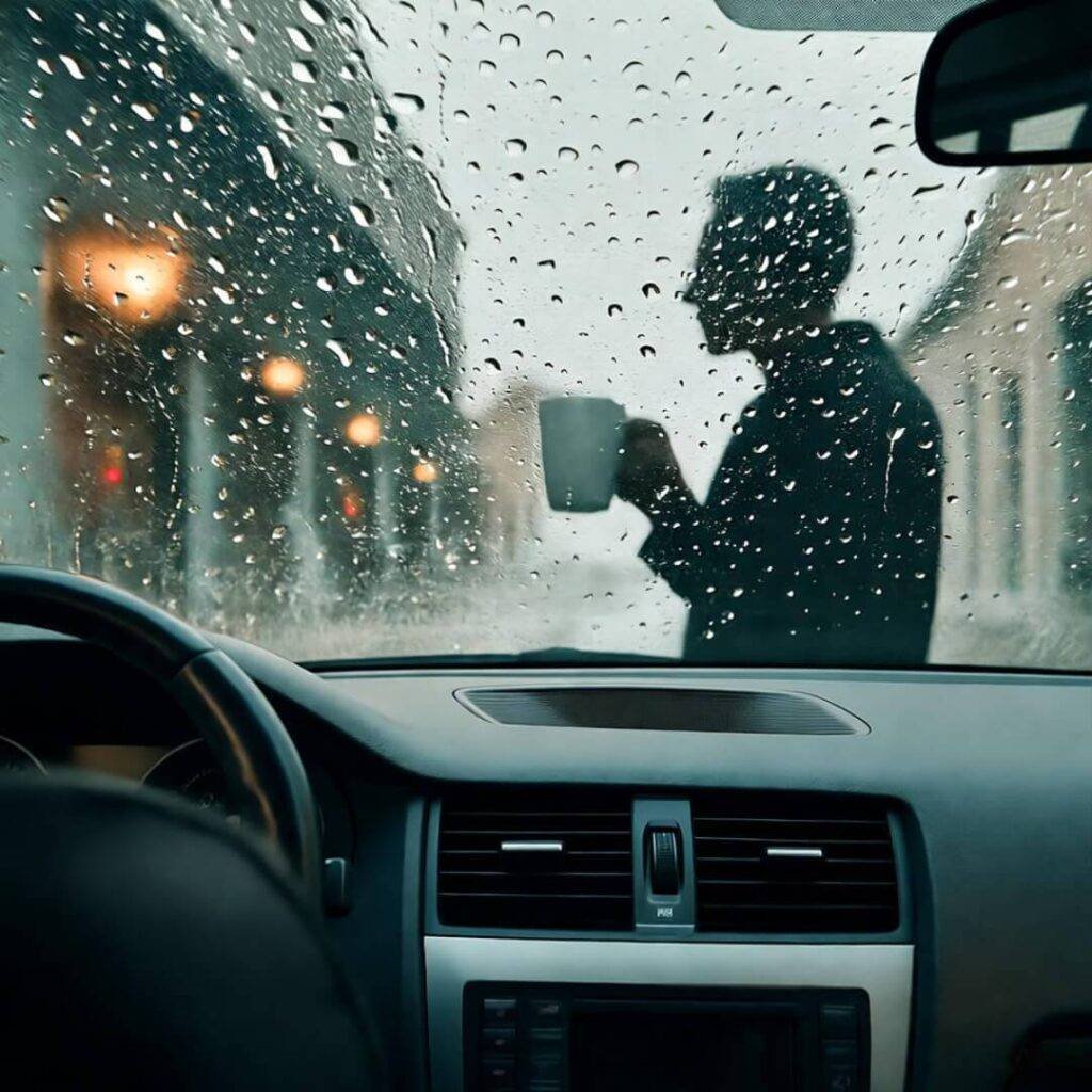Rainy window reflects dashboard win, mug.